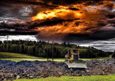 A bulldozer under an image of a fiery clouds